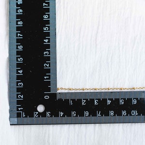 Może przedstawiać: Złoty naszyjnik w postaci łańcuszka mierzony przy użyciu czarnej linijki. Łańcuszek ma około 25 cm długości.