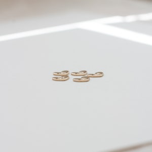 May include: Six gold heart-shaped charms with a textured surface.