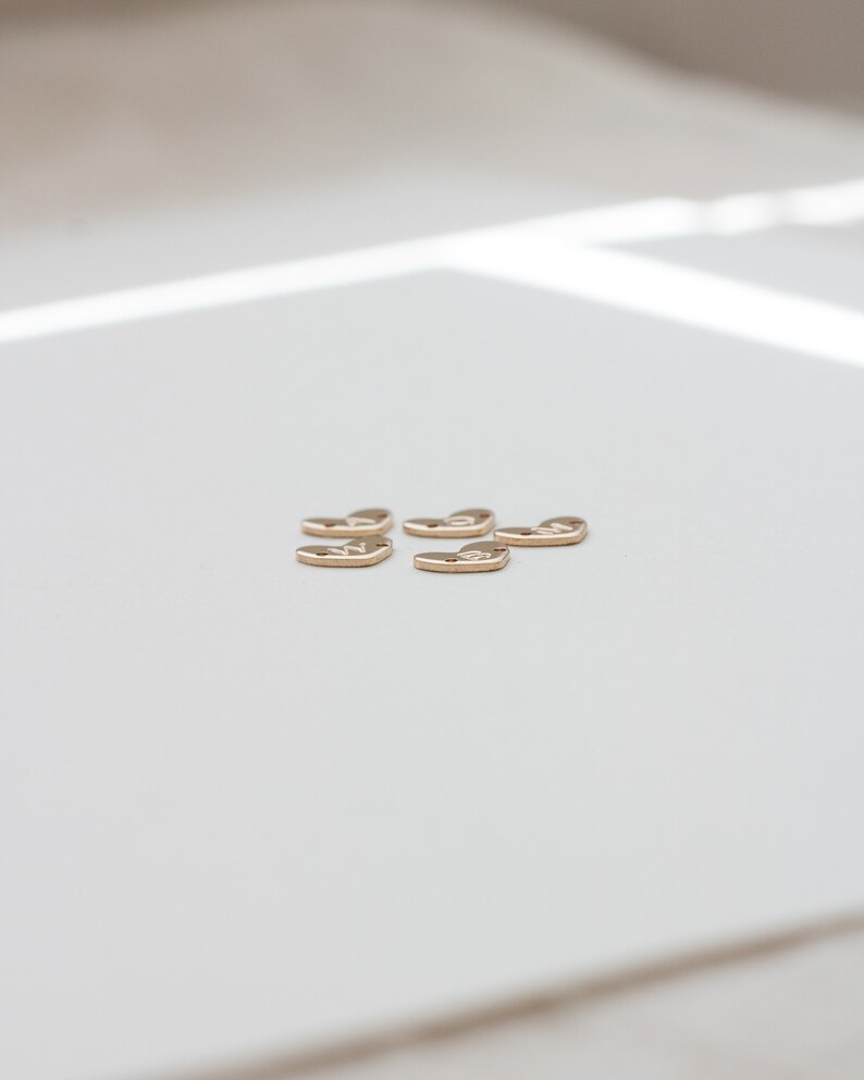 May include: Six gold heart-shaped charms with a textured surface.