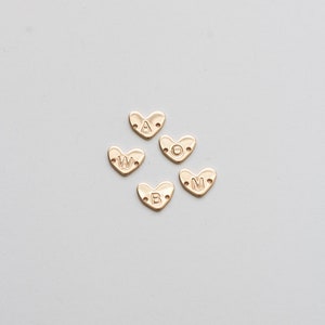 May include: Five gold heart-shaped charms with the letters A, W, O, B, and M.