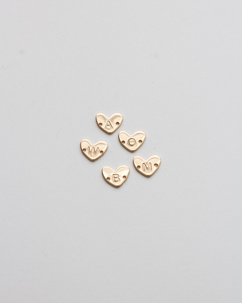 May include: Five gold heart-shaped charms with the letters A, W, O, B, and M.