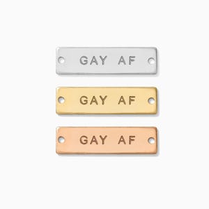 May include: Three silver, gold, and rose gold metal bar charms with the text "GAY AF" engraved on each.