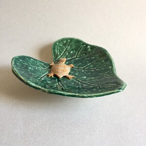 May include: A ceramic dish shaped like a green leaf with a small turtle figurine on top.