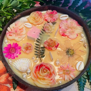 Op de afbeelding: Een ronde houten kom gevuld met verschillende kleurrijke wax melts, waaronder bloemen, schelpen en bladeren. De wax melts zijn in een decoratief patroon gerangschikt en klaar om te worden gebruikt in een wax warmer.