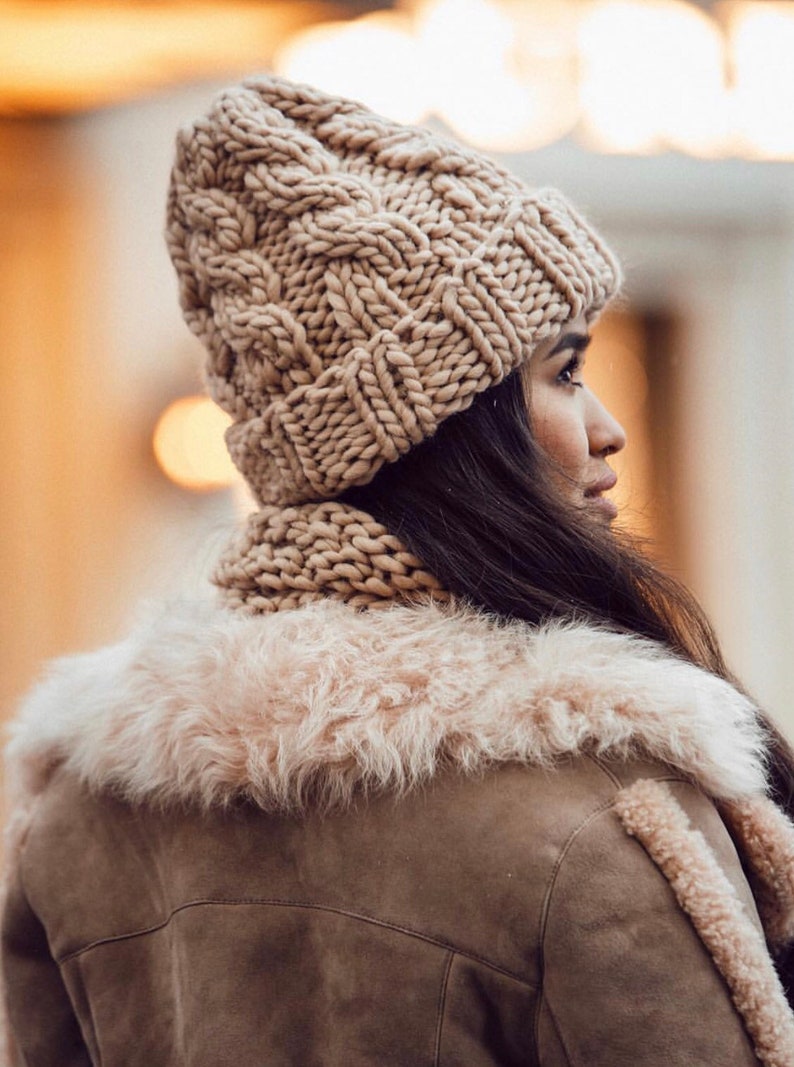 May include: A woman wearing a brown knitted hat and matching scarf, with a brown faux fur collar jacket.