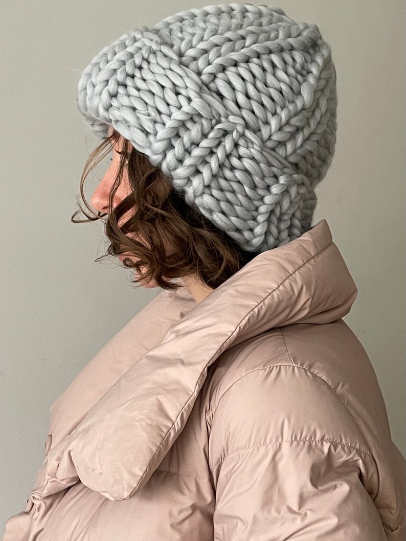 May include: A light grey chunky knit beanie hat with a slouchy fit. The hat is made with thick yarn and has a simple, textured design.