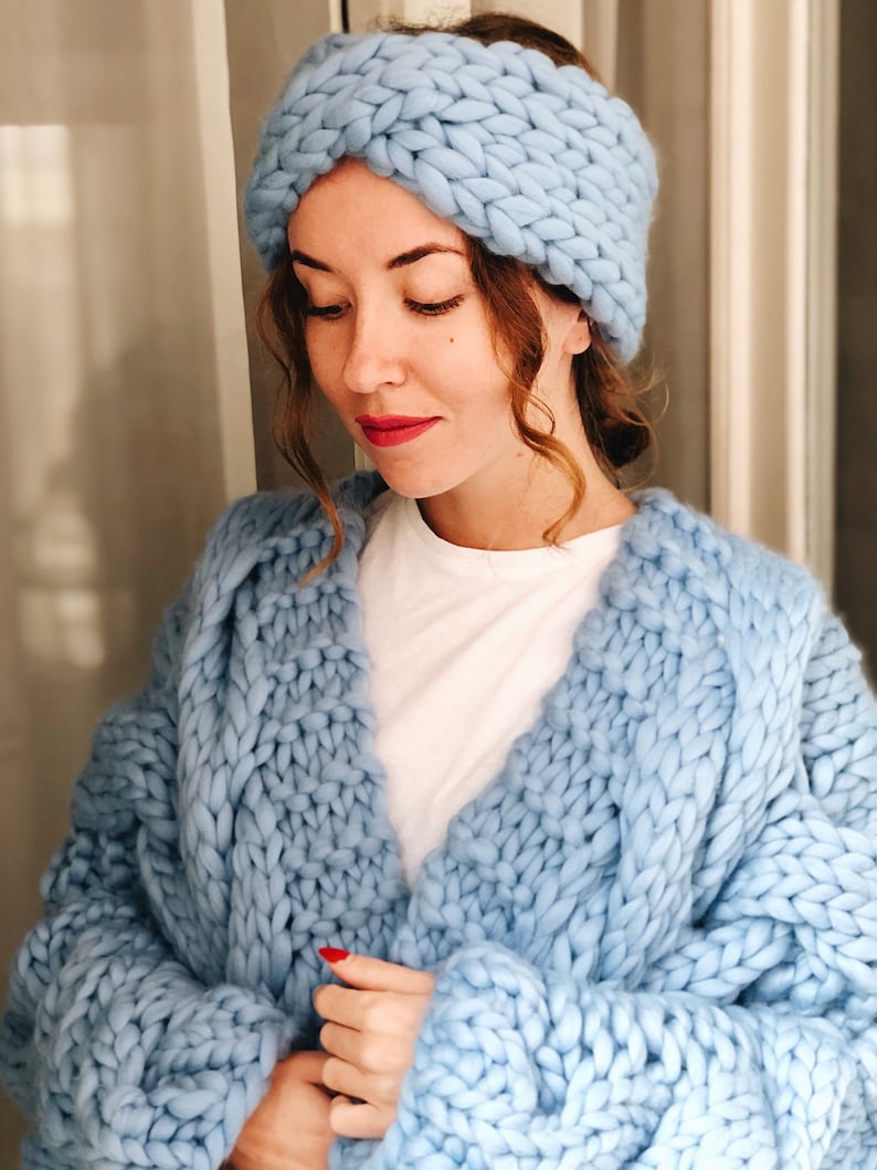 May include: A light blue knitted headband and a matching chunky knit cardigan. The cardigan has a loose fit and a v-neck.