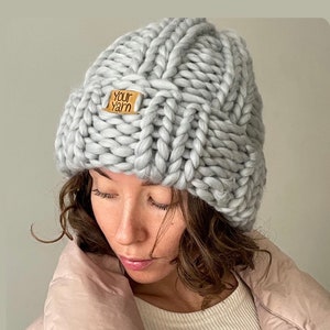 May include: A grey knitted beanie with a brown leather tag that says "Your Yarn".