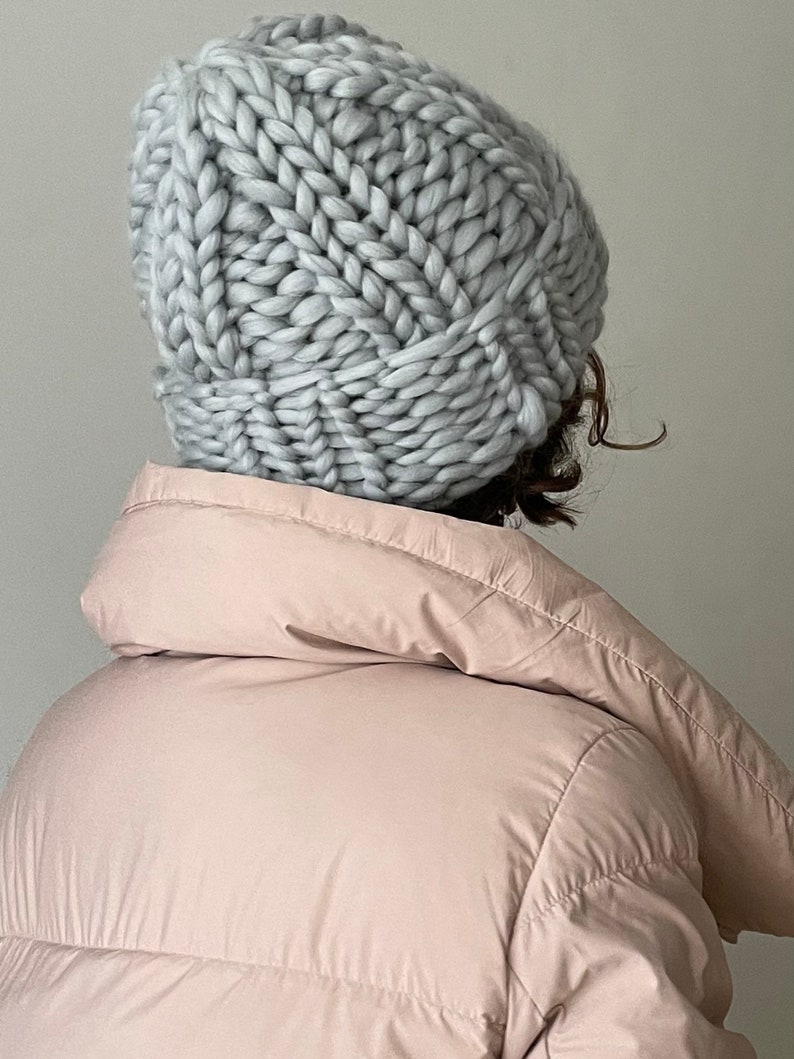 May include: A light grey chunky knit beanie hat. The hat is made with thick yarn and has a slouchy fit.