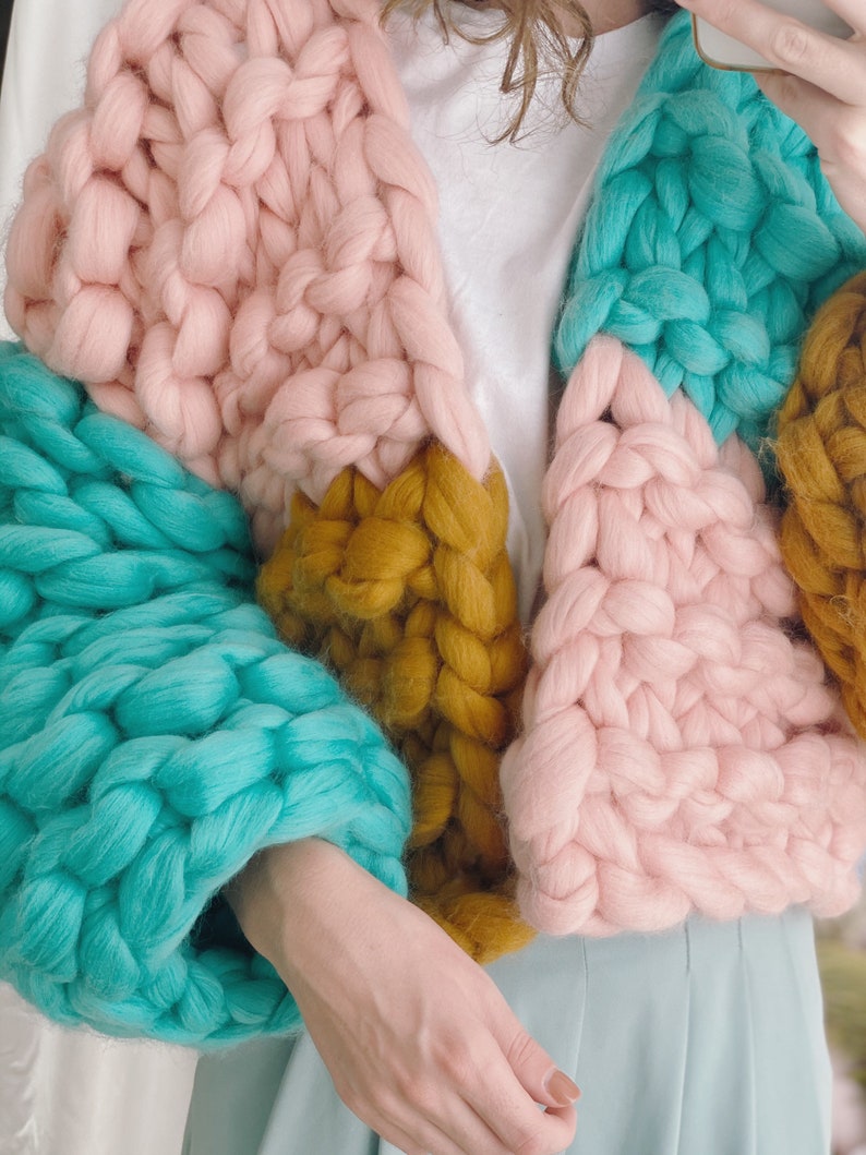 Pode incluir: Um casaco de malha grossa com um design de blocos de cores em rosa, azul-turquesa e amarelo mostarda.