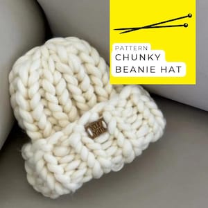 Peut inclure: Un bonnet en tricot blanc épais avec une étiquette en cuir marron qui dit "Your Yarn".