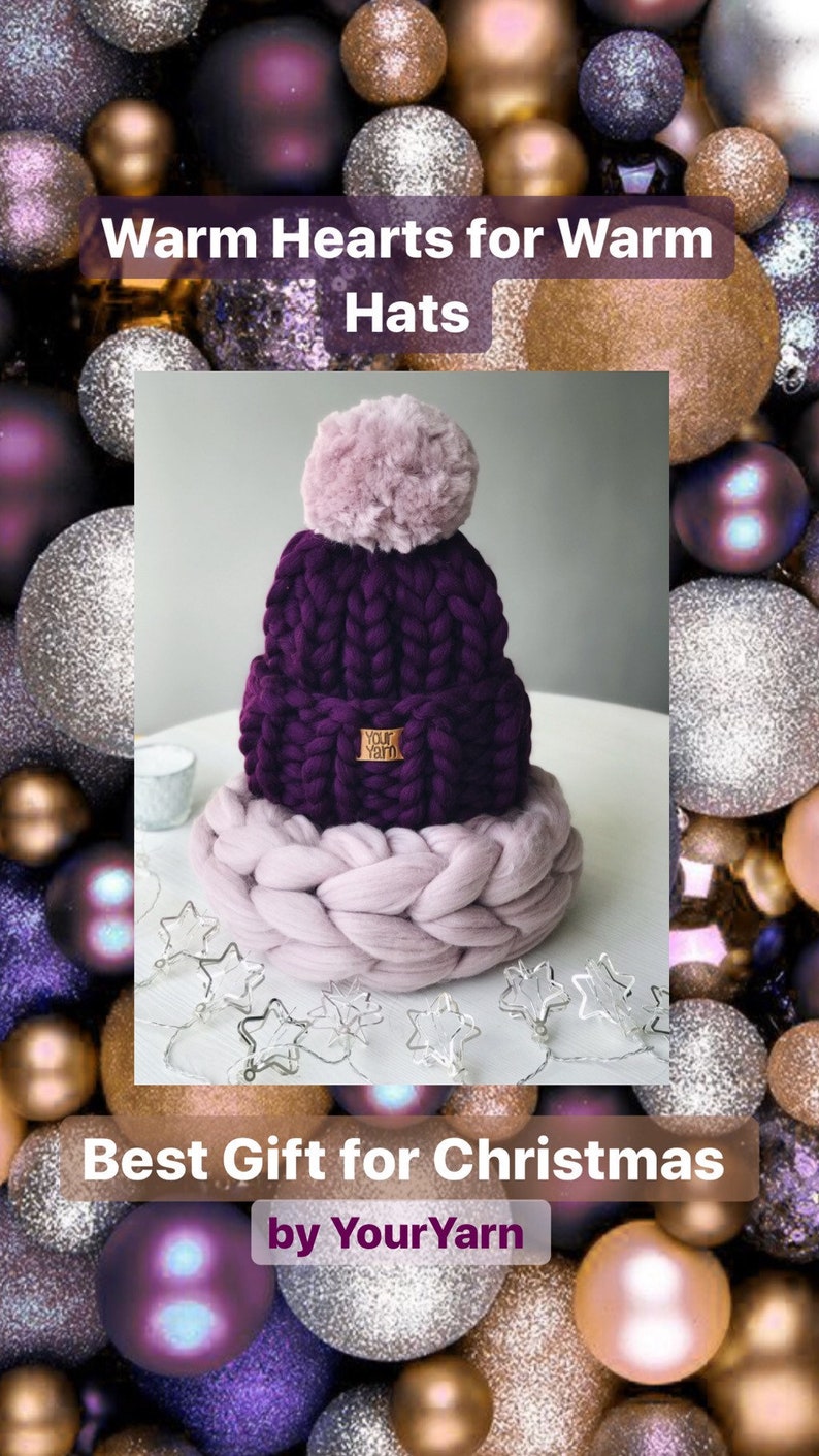 May include: A purple knitted beanie with a fluffy pink pom pom and a brown leather tag that says "Your Yarn". The beanie is sitting on a thick, light pink knitted circle. The background is a collection of sparkly purple, gold, and silver ornaments.