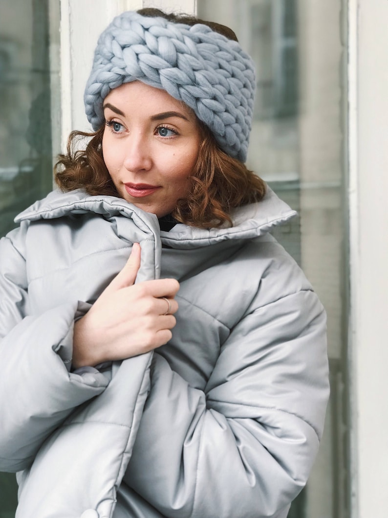 May include: A woman wearing a light blue knitted headband and a light blue puffer jacket.