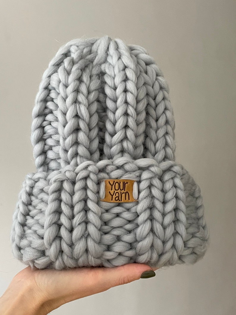May include: A grey knitted beanie with a brown leather tag that says "Your Yarn".