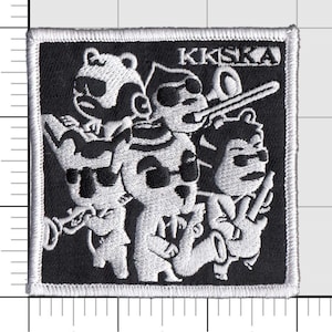 May include: Black and white embroidered patch with the text "KKSKA" and a design of four cartoon animals playing musical instruments.