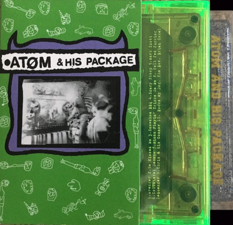 May include: A green cassette tape with a purple and black label that says "ATOM & HIS PACKAGE". The cassette tape is in a clear plastic case with a green border. The label has a black and white photo of a person in a room.