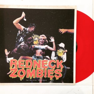 May include: Red vinyl record with a red and yellow graphic of the words "Redneck Zombies" and the text "The Official Soundtrack". The album cover features a group of people in a dark setting.