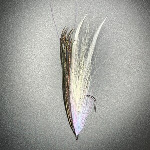 May include: A white and brown fly fishing lure with a long, thin body and a hook at the end. The lure is made of feathers and other materials.