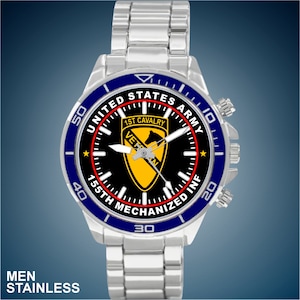 May include: Stainless steel watch with a blue and black face. The watch face features the text "UNITED STATES ARMY", "1ST CAVALRY", and "155TH MECHANIZED INF". The watch has a silver band and a blue bezel. The text "MEN STAINLESS" is at the bottom.