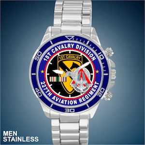 May include: A silver watch with a blue face and a black and yellow emblem. The emblem says "1st Cavalry" and "227th Aviation Regiment".