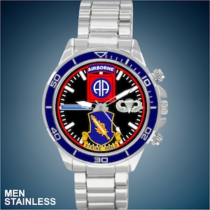 May include: A silver stainless steel watch with a black face and blue bezel. The face features a military insignia with the words "Airborne", "Strike", and "Hold".