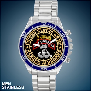 May include: A silver watch with a blue bezel and a black face. The face features the words "United States Army" and "Ranger Airborne" in gold lettering. The watch also features a gold Ranger tab and a gold Airborne wings.