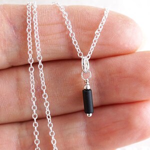 May include: A silver chain necklace with a small black rectangular pendant.