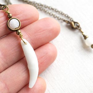 Peut inclure: Un collier avec un pendentif en forme de dent blanche, une chaîne en laiton et une perle d'agate blanche. Le pendentif est une dent réaliste avec une finition blanche lisse.