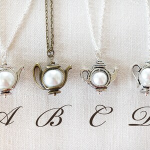 May include: Four silver and bronze necklaces with teapot pendants and white pearl accents. The pendants are labeled A, B, C, and D.