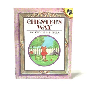 Könnte beinhalten: Ein Buch mit dem Titel "Chester's Way" von Kevin Henkes. Das Cover zeigt eine gerahmte Illustration einer Maus, die Krocket in einem Garten spielt. Der Rahmen hat ein Blumenmuster. Das Buch hat ein "Picture Puffins"-Logo.
