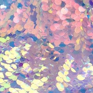 May include: A fabric material covered in round, iridescent sequins that reflect light in shades of pink, blue, and yellow. The sequins are densely layered and attached to a sheer mesh base, creating a shimmering, multi-colored surface texture.