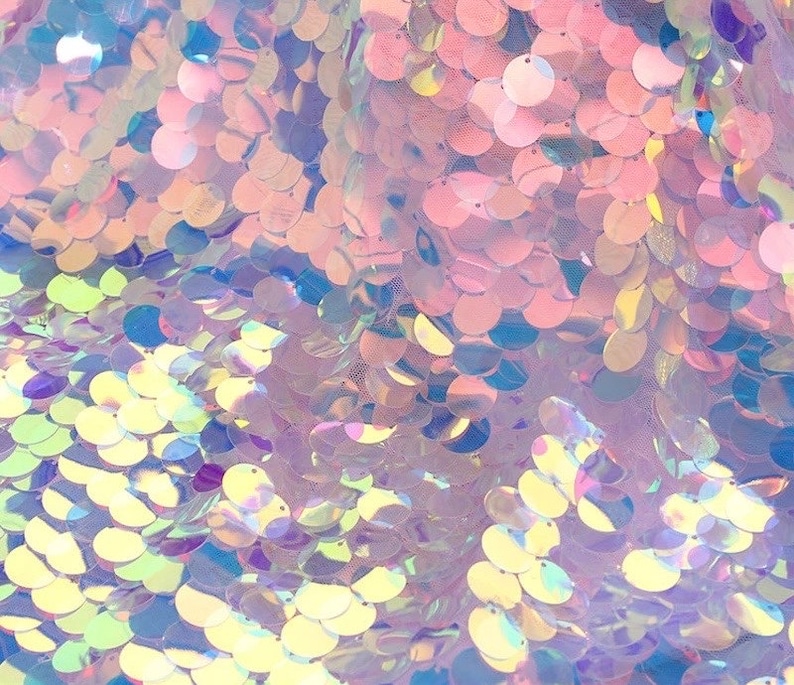 May include: A fabric material covered in round, iridescent sequins that reflect light in shades of pink, blue, and yellow. The sequins are densely layered and attached to a sheer mesh base, creating a shimmering, multi-colored surface texture.