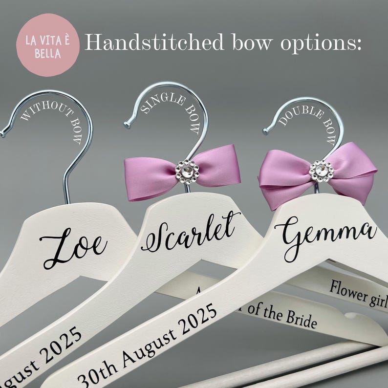 May include: White wooden hangers with silver hooks, personalised with names and dates. Some hangers feature handstitched lavender bows with crystal embellishments. Text includes "Loe", "Scarlet", "Gemma", and "30th August 2025".