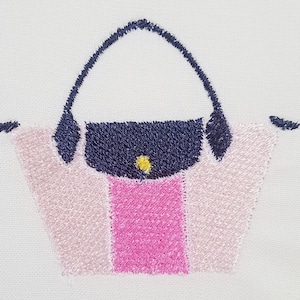 May include: Embroidered design of a pink and navy blue handbag with a yellow button.