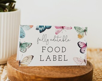 May include: A white card with a watercolour butterfly design and the text "fully editable FOOD LABEL". The card is sitting on a wooden stand.