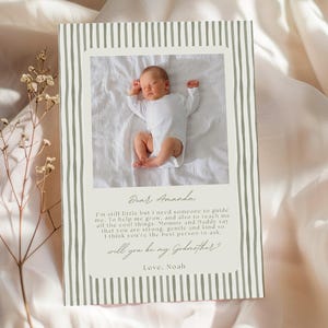 Puede incluir: Tarjeta de anuncio de bebé con foto de un recién nacido con un body blanco. La tarjeta tiene un borde a rayas y el texto: "Querida Amanda, ¿quieres ser mi madrina? Con amor, Noah."