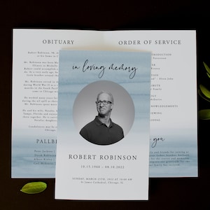 Pode incluir: Um programa de funeral com um fundo de aquarela azul e uma foto em preto e branco de um homem em um círculo. O programa inclui a ordem do serviço, um obituário e o texto "em memória carinhosa". O programa é para Robert Robinson, 10.15.1960 - 08.10.2022. O serviço será realizado no domingo, 25 de março de 2022 às 10:00 AM na Catedral de São Tiago, Chicago, IL.