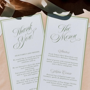 May include: Two rectangular white paper cards with sage green borders. One card reads Thank You! with a message to family and friends. The other card reads The Menu, listing starters, main course, and dessert options in elegant dark green script.