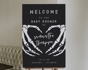 May include: Black and white welcome sign with a skeleton hand heart design. The sign reads "Welcome to the Baby Shower of Samantha Thompson 10.31.XX Chicago, Illinois".