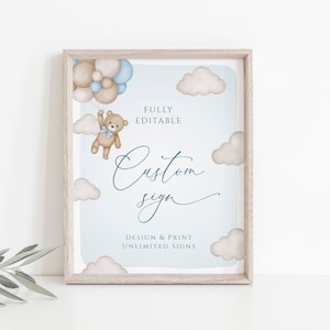 May include: A framed sign with a light blue background features a watercolor illustration of a teddy bear floating with balloons. The sign includes the text "Custom sign" in cursive and "Design & Print Unlimited Signs". The frame is a light wood color.