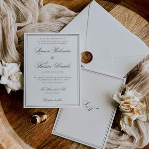 Puede incluir: Elegante conjunto de invitaciones de boda con una invitaci&oacute;n formal, una tarjeta de confirmaci&oacute;n de asistencia y un sobre con un sello de cera. La invitaci&oacute;n incluye los nombres "Lauren Robinson" y "Thomas Daniels" y los detalles del evento. El conjunto est&aacute; dispuesto sobre una bandeja de madera con detalles florales.