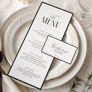 May include: Elegant wedding menu and place card set. The menu features a black border and the word "MENU" in a stylish font. The place card displays the name "Catherine Turner". Both are on a white plate with a decorative edge.
