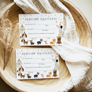 May include: Two white adoption certificates with a colorful dog theme. The certificates have spaces to fill in the name of the person adopting and the pet's name. The text on the certificate reads "Adoption Certificate" and "This certifies that... has adopted..."