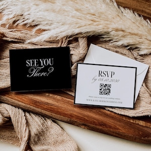 May include: Two invitation cards with text, "See You There?" and "RSVP by 08.10.2030" with a QR code, on a wooden tray. The cards are black and white with elegant fonts. Dried ornamental grass and a beige cloth are in the background.