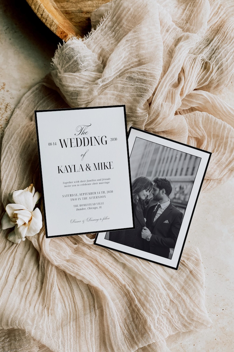 May include: Two wedding invitations with black borders rest on a beige fabric. The invitation on the left has the text "The Wedding of Kayla & Mike" and event details. The right invitation has a black and white photo of a couple.