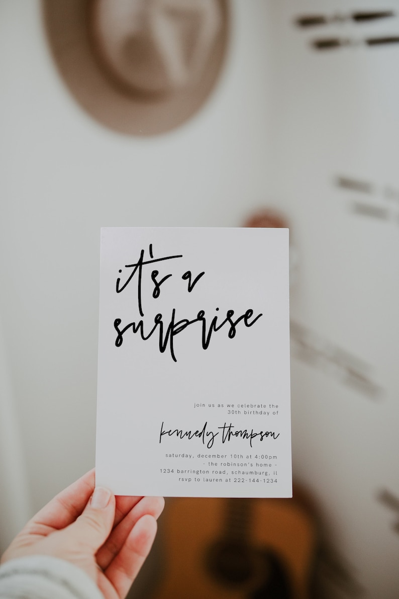 May include: A white card with black text that reads "it's a surprise" and details for a surprise party for Kennedy Thompson's 30th birthday. The party will be held on Saturday, December 10th at 4:00 PM at the Robinson's home, located at 1234 Barrington Road, Schaumburg, Illinois. RSVP to Lauren at 222-144-1234.