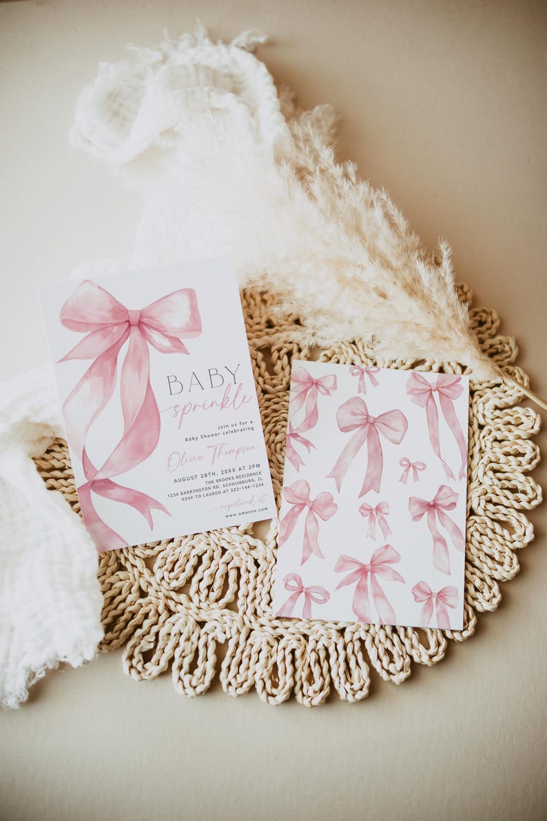 Pu&ograve; includere: Due inviti per baby shower con fiocchi rosa ad acquerello. Un invito recita "BABY sprinkle" e include i dettagli dell'evento. La seconda carta presenta un motivo di fiocchi rosa. Le carte sono su un sottobicchiere intrecciato con elementi decorativi.