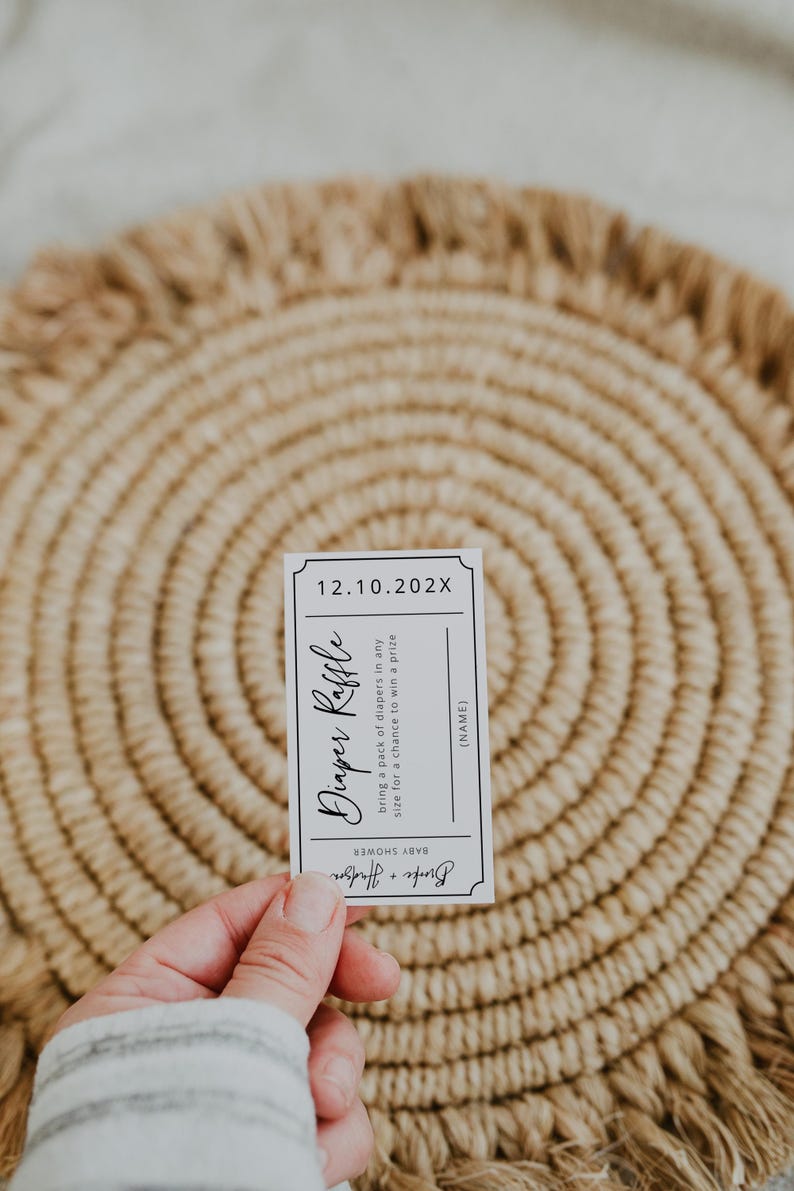 May include: A white ticket with black text for a diaper raffle. The text reads "Diaper Raffle" and "bring a pack of diapers in any size for a chance to win a prize". The date "12.10.202X" is printed at the top of the ticket.