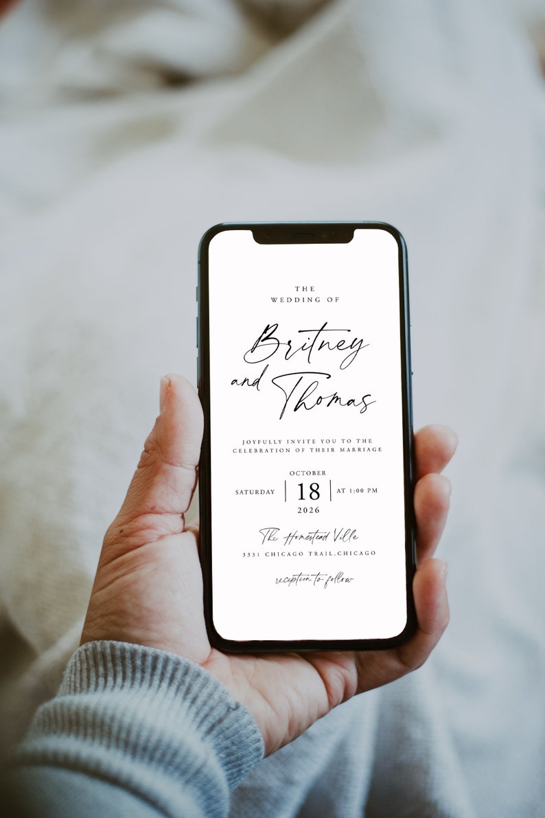 May include: A white wedding invitation on a smartphone screen. The invitation reads "The Wedding of Britney and Thomas" with the date and time of the wedding: "Saturday, October 18, 2026 at 1:00 PM". The location is "The Homestead Ville, 3331 Chicago Trail, Chicago" with the words "reception to follow" at the bottom.