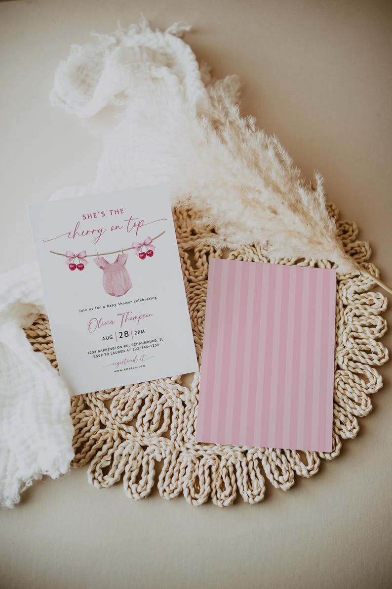May include: A baby shower invitation with the text "She's the cherry on top" and a pink onesie graphic. The invitation includes details for Olivia Thompson's baby shower on August 28th at 2 PM. A pink striped card is next to the invitation.